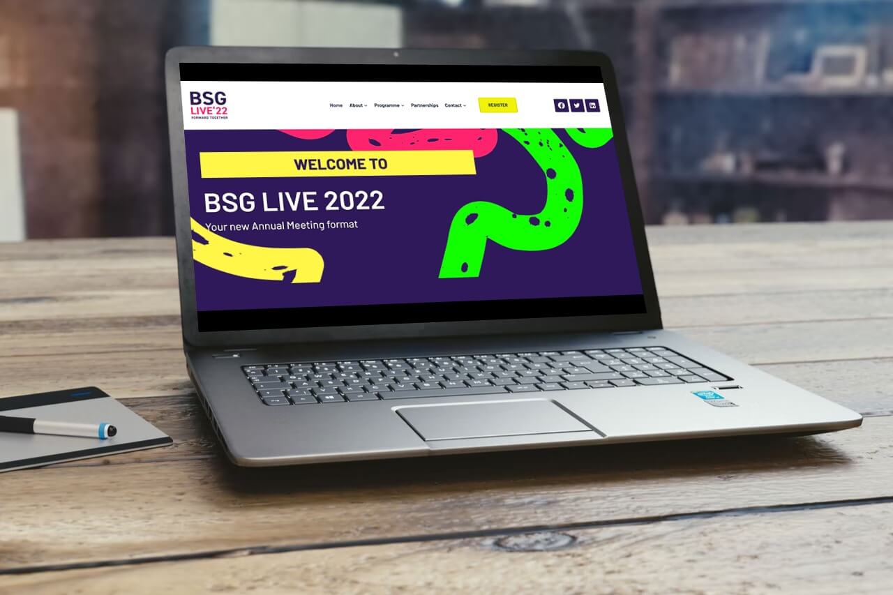 imge of BSG Live website on laptop on wooden table