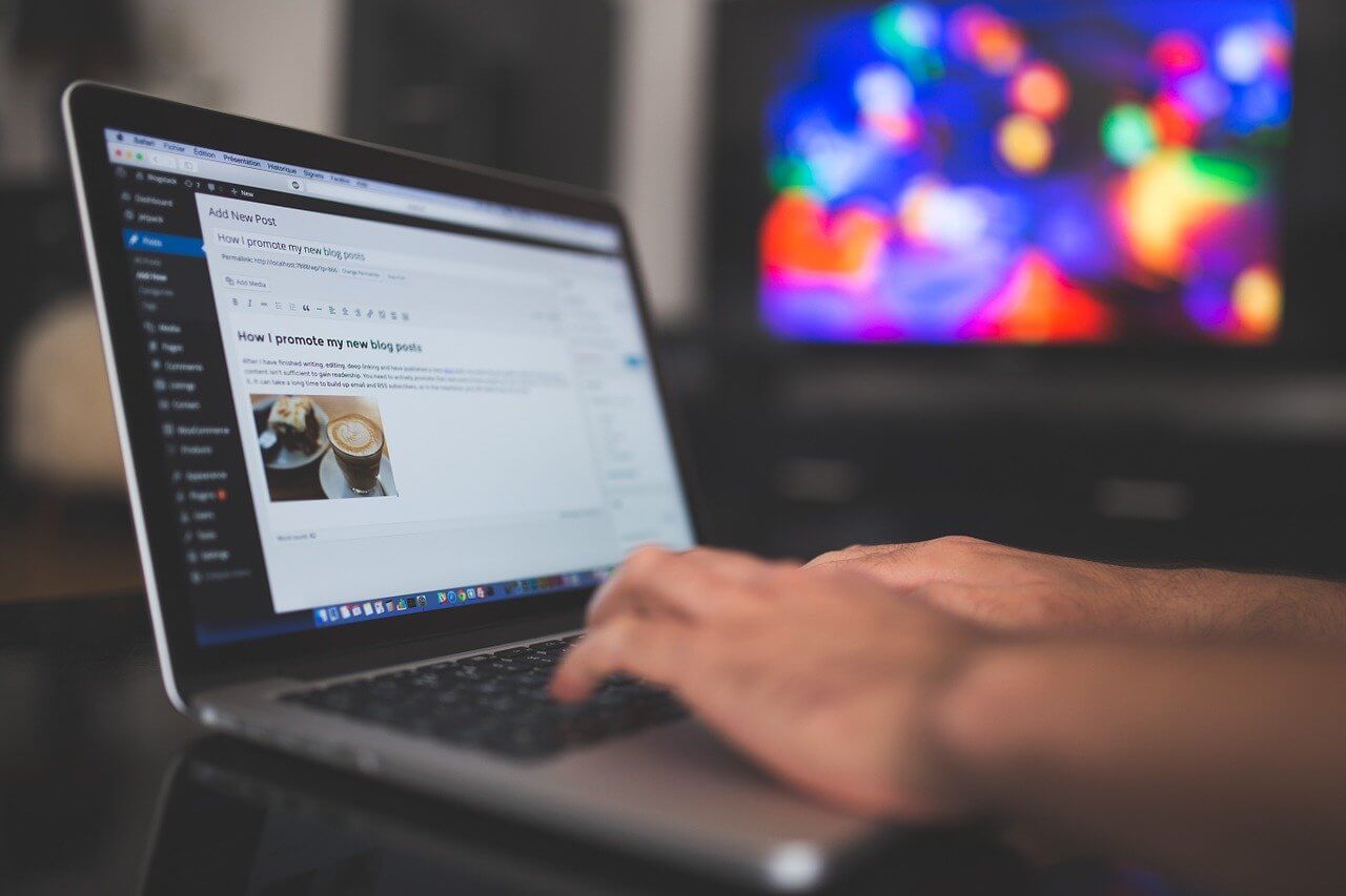 Image of a laptop with person typing a blog post into a wordpress website